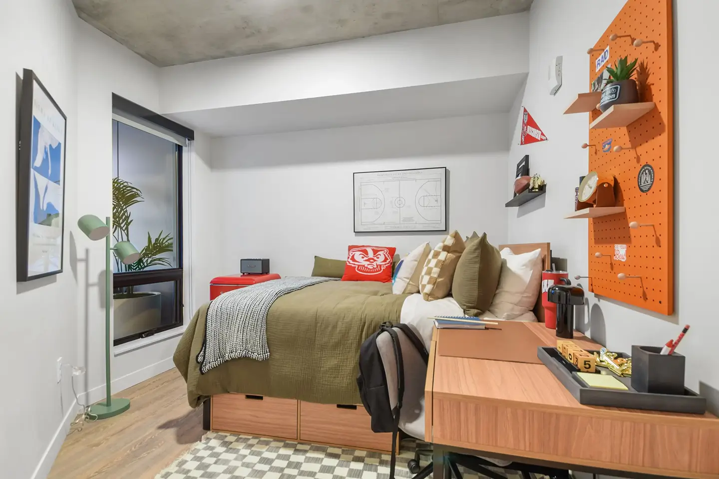 Furnished apartment bedroom with a bed, under-bed dresser, and desk.